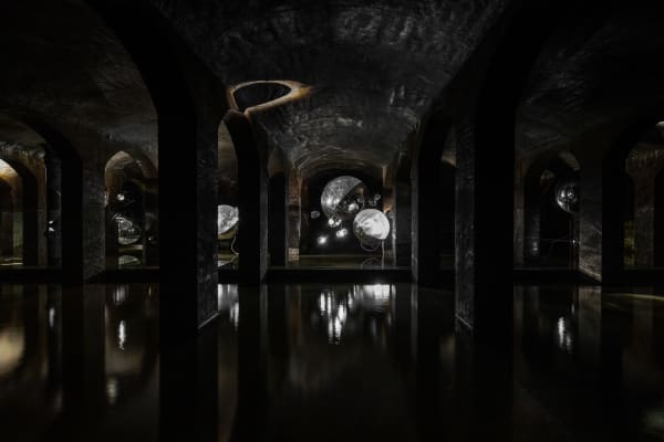 image of Saraceno sculptures hanging in dark room over water
