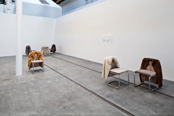 image of chairs with fur coats hanging off of them