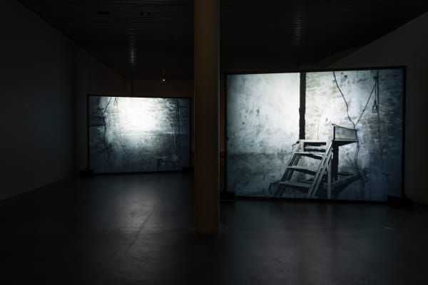 Susan Philipsz's film still image, two channel projection of concrete building facades in dark room