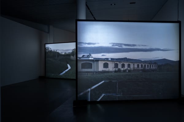 Susan Philipsz's film still image, two channel projection of concrete building facades in dark room
