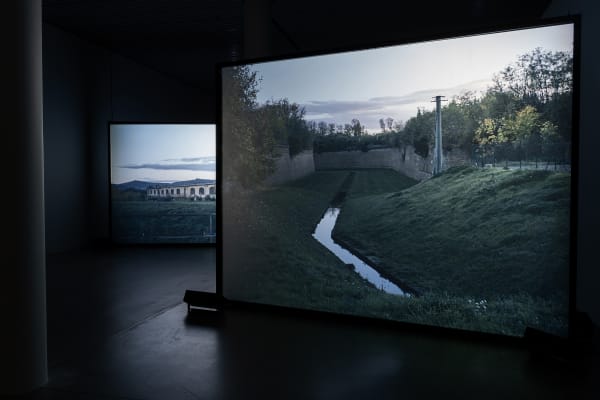 Susan Philipsz's film still image, two channel projection of concrete building facades in dark room