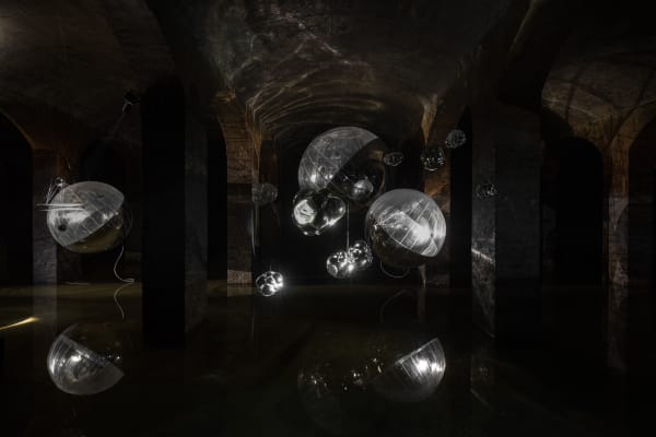 image of Saraceno sculptures hanging in dark room over water