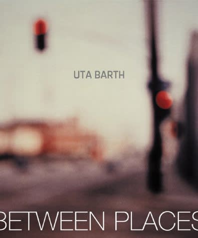 Exhibition catalogue cover for Uta Barth exhibition "in between places". Blurred photo of a traffic light hanging over a street corner. Grey text: Uta Barth, between places