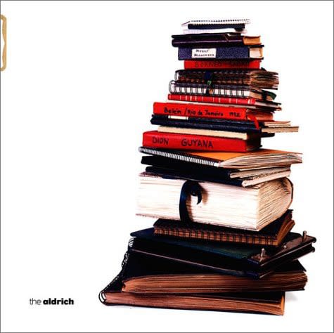 Exhibition catalogue book cover. Photo of a tall stack of books, notebooks, and sketchbooks on a white background.