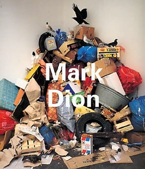 Exhibition catalogue cover. Photo of a tall ile of cardboard boxes, plastic bags, tires, taxidermied birds and other trash in a corner. White title text: "Mark Dion"