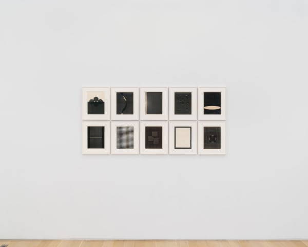 a group of ten framed works on a white wall