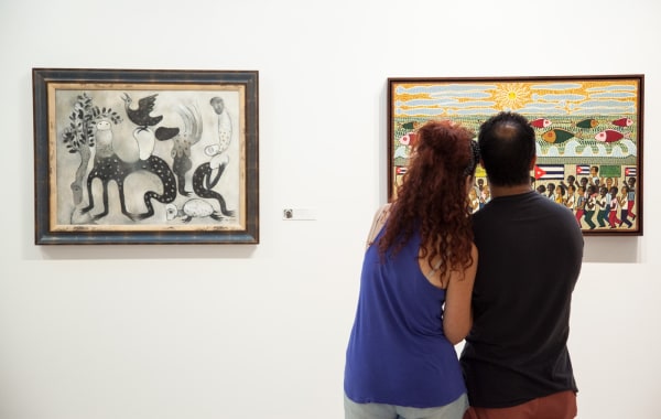 Installation shot of exhibition of the von Christierson Collection. A couple stands in front of a painting.