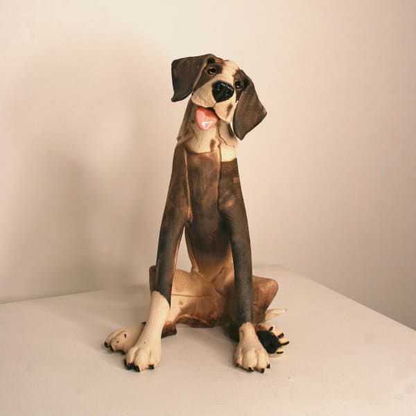 Virginia Dowe-Edwards ceramic dog in a steated position with it's tongue hanging out, with raku fired patches