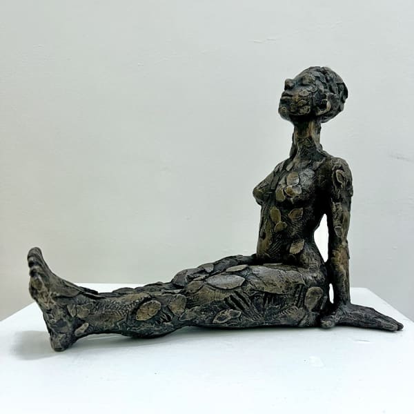 Carol Peace textured bronze resin sculpture o female figure in a seated position, legs straight ahead of her and hands placed on ground behind supporting her upright posture