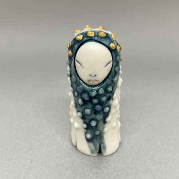 Marina Bauguil tiny sculpture of a plant spirit in white with a blue hood and gold droplets.