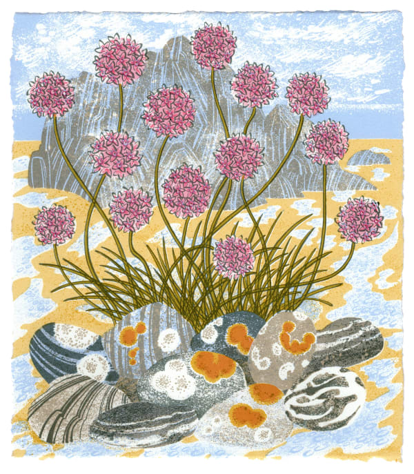 Angie Lewin screenprint of sea pinks growing on a pebbly beach with a large rock in the background and blue sky
