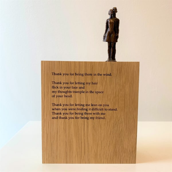 Carol Peace sculpture of two tiny figures, male and female stood close together on an oak block. The figures are smooth in texture and the colour is a rich bronze. The text of a poem is printed on the oak.