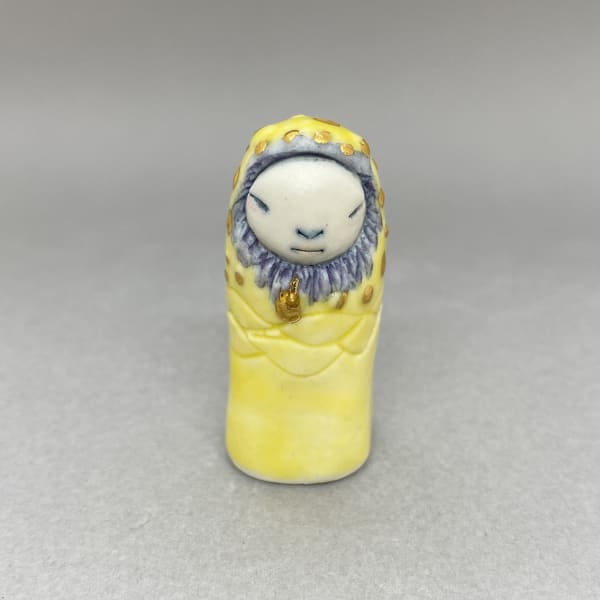 Marina Bauguil tiny sculpture inspired by Japanese kami culture in yellow with blue highlights and gold drops on its head.