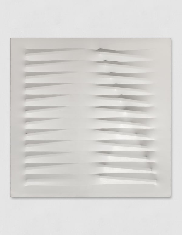 A white wall sculpture made with vinyl tempera laid over nails to create an undulating pattern.