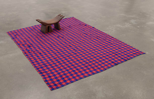 A curved wooden headrest with three divisions on either side and three legs on a red and blue patterned cloth