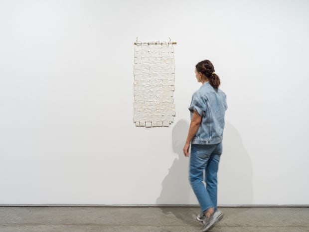 Titanium White No. 2 (2014) is composed of woven canvas strips that Sharif paints over, suspends, and binds using a...