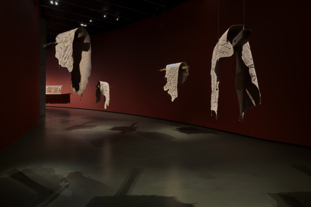 Prologue, 2024, Beaded cow hides hung on antique wooden pillars with aluminium saddles, Dimensions variable.