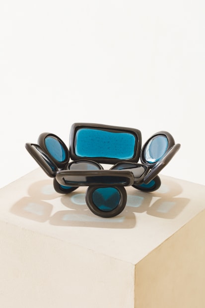 MIRROR, 2023 This mirror pairs a fused-glass surface with a bronze base composed from the modular rings that define the...