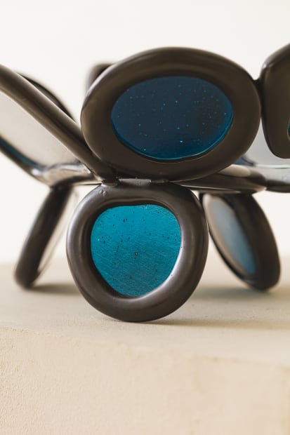 MIRROR, 2023 This mirror pairs a fused-glass surface with a bronze base composed from the modular rings that define the...