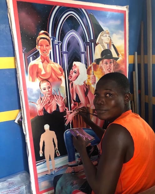 Photo of an artist in an orange shirt painting a scene of 4 women