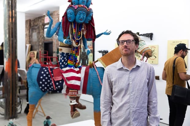 photograph of Artist Ravi Zupa in front of his sculpture of a blue figure on a horse