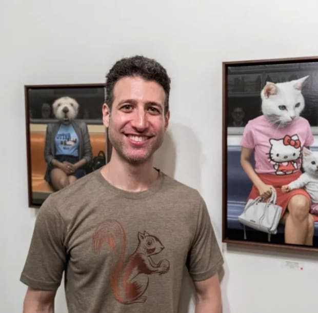 portrait of Matthew Grabelsky standing in front of his animal / human paintings