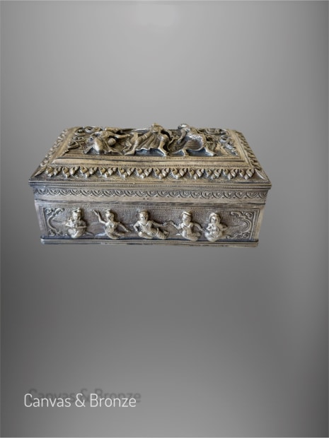 Ornate silver box with intricate relief sculptures and decorative motifs.