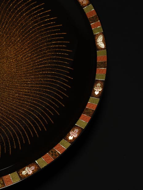 In maki-e, designs are created by scattering powdered gold, silver, and other precious materials on to urushi, the refined sap...