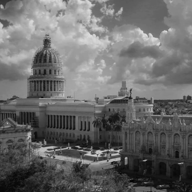 Black & white photograph of Havana city centre. It shows a large domed building in the focal area with clouds building behind it.