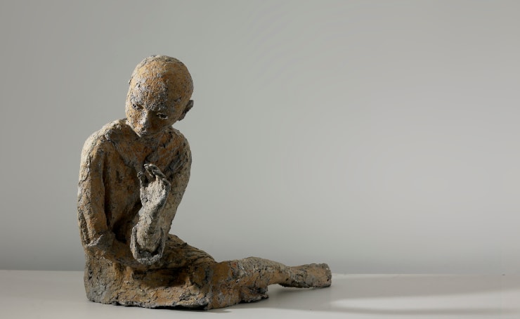 The front of a reclining woman who is made by paper mache.