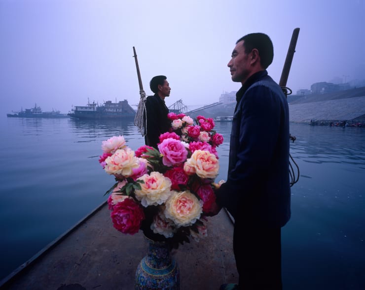 Two Bang Bang men and two vases of flowers are on the boat.