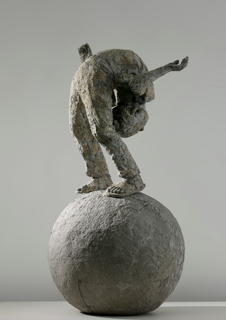 A body bends his body and stands on a ball.