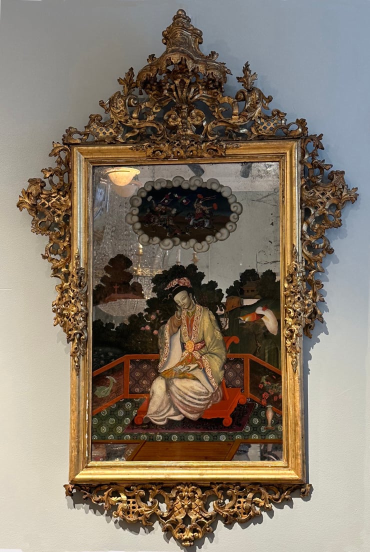 Mirror in gilded wood with carved top and painting of an oriental figure, Prob. Germany, 18th century