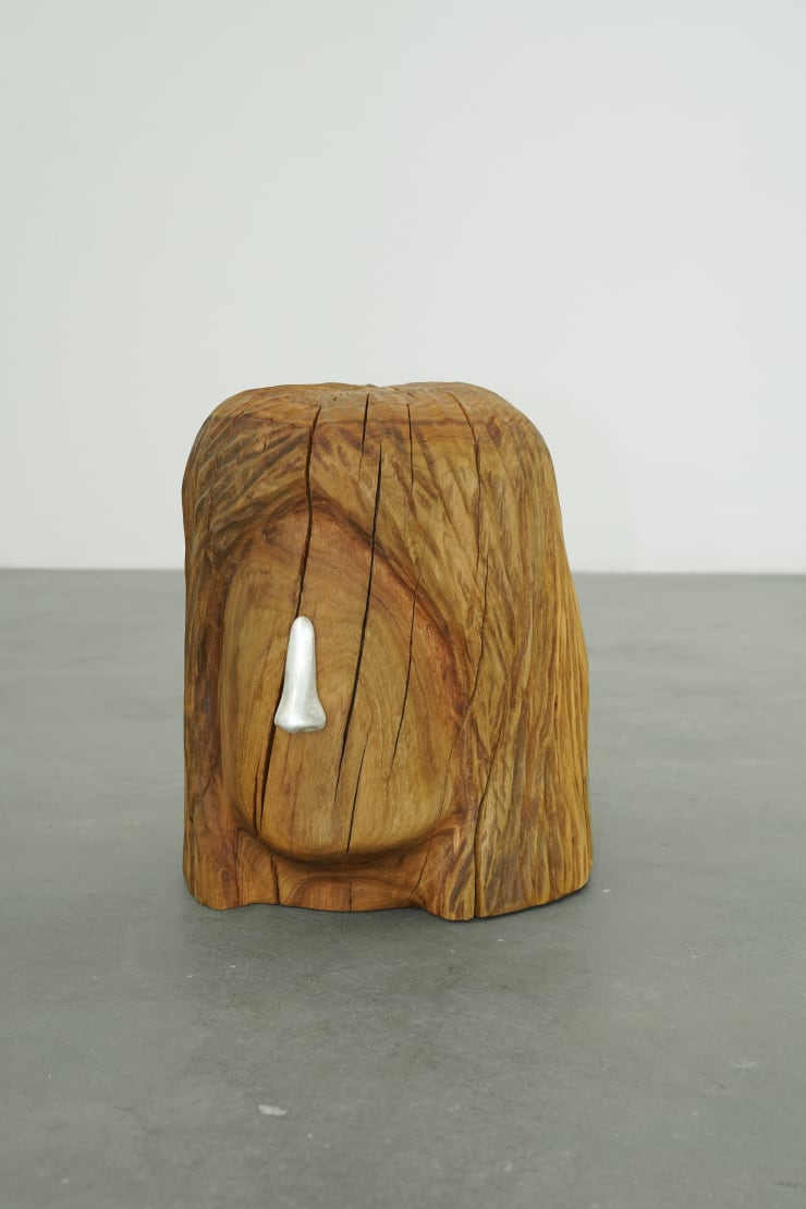 wooden stool shaped into a head with metal nose