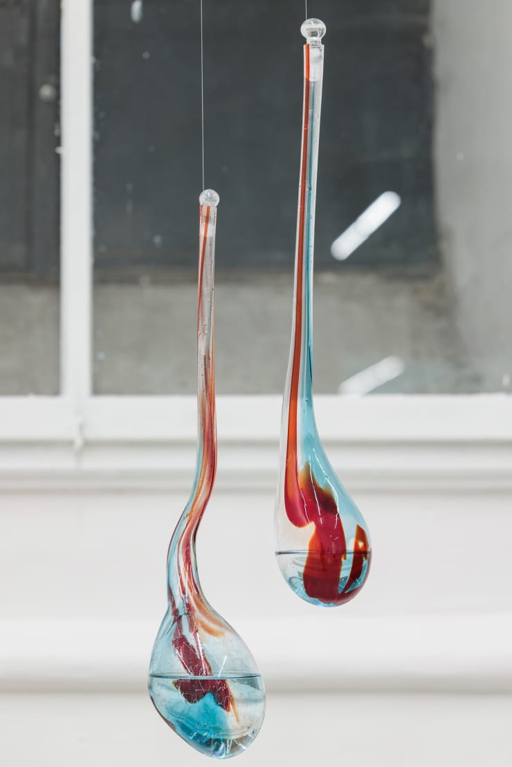 Isabella Séville Fürnkäs The Desiring Machines, 2025 A pair of individual mouth-blown red ruby glass drops, ethanol, engraved words. left: 49cm, Ø 33 cm right: 52cm, Ø 27