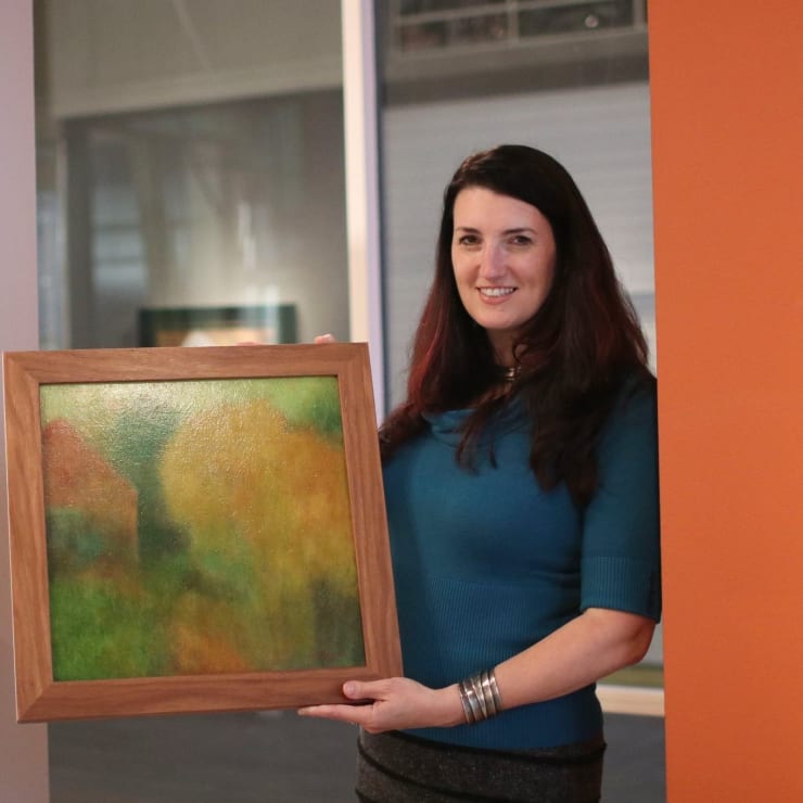 Karin Clarke with a painting by Mark Clarke. Photo by Athena Delene.