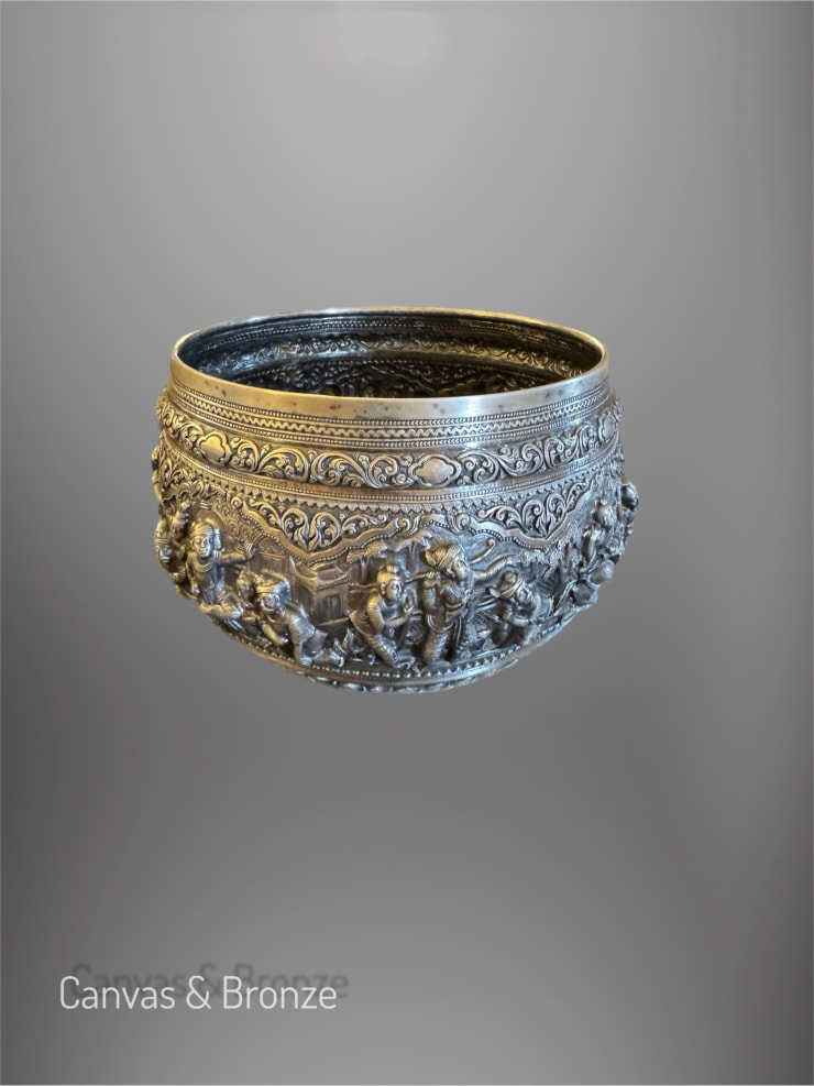 Ornate silver bowl with intricate relief carvings depicting historical and cultural scenes, featuring detailed patterns and figures.