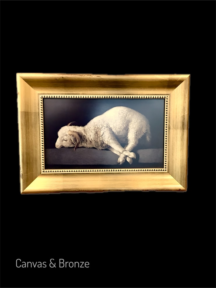 Lamb of God painting in a gold frame against a black background.