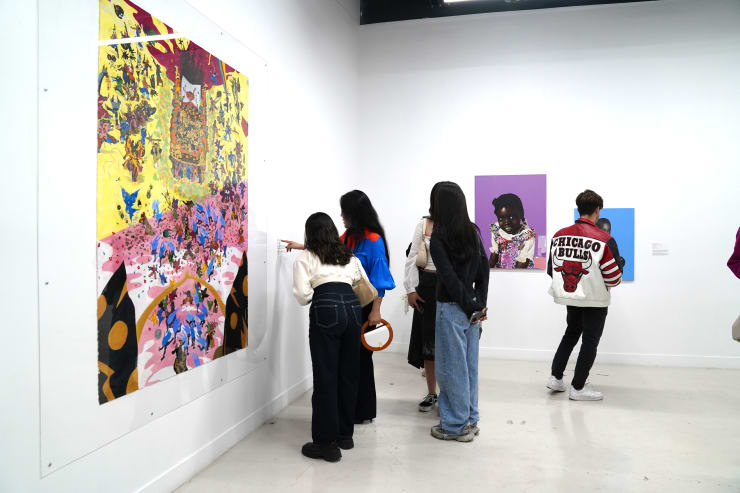 photograph of the gallery with paintings on the walls and a crowd of people inside