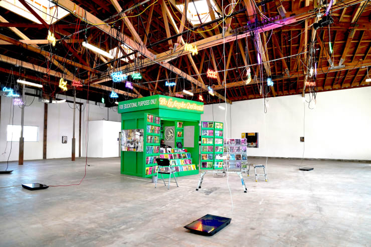 photograph of a newspaper stand installation with neon signs hanging above by Devin Troy Strother