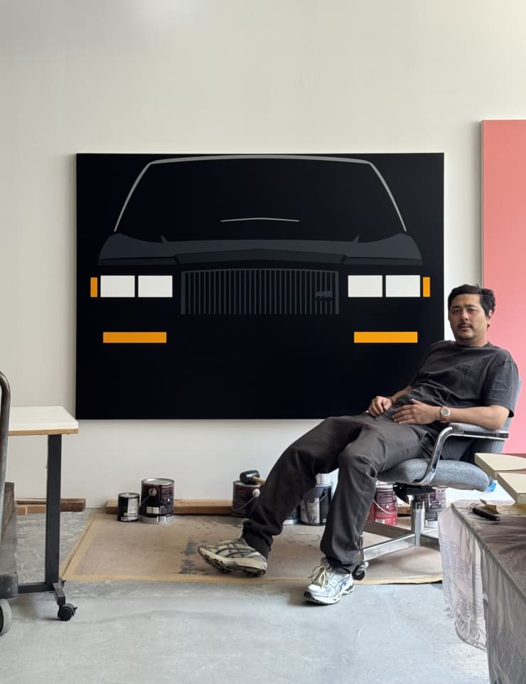 photo of the artist in his studio with a painting of a car in the background