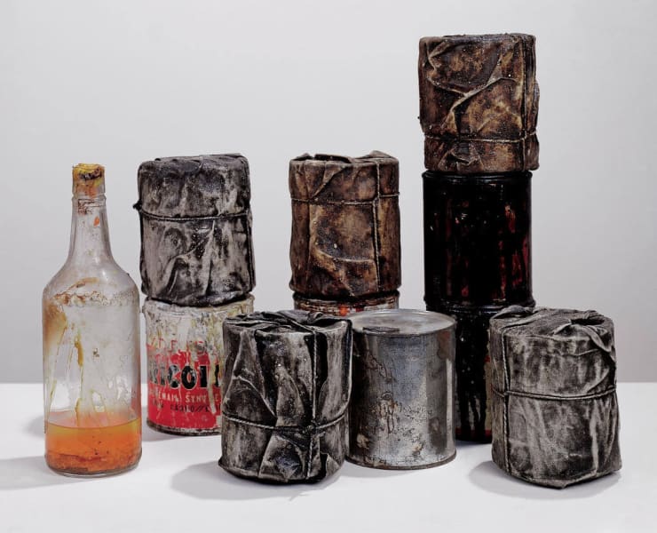 Christo Wrapped Cans, 1958-59 Group of ten cans, five wrapped, diameter of each: 4 to 4 1/8″ (10 to 10.5 cm), height of each: 4 3/4 to 5 1/8″ (12 to 13 cm), one bottle: 10 3/4 x 3″ (27 x 7.5 cm) Fabric, rope, lacquer, paint, sand, ten cans and a bottle