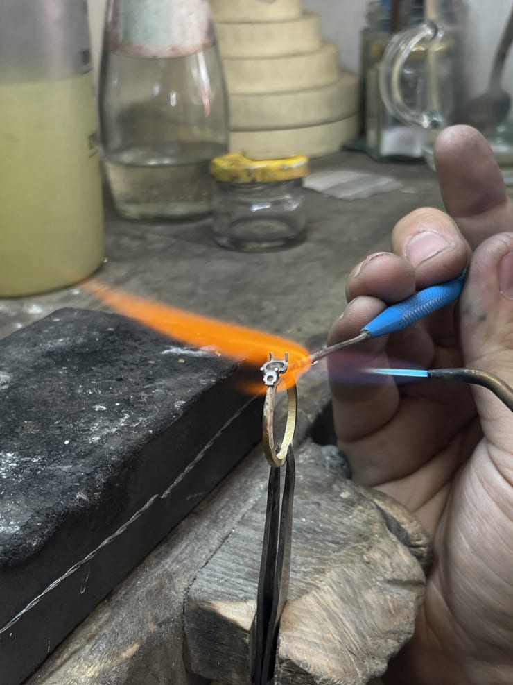 Ring being soldered on jewellers bench with flame.