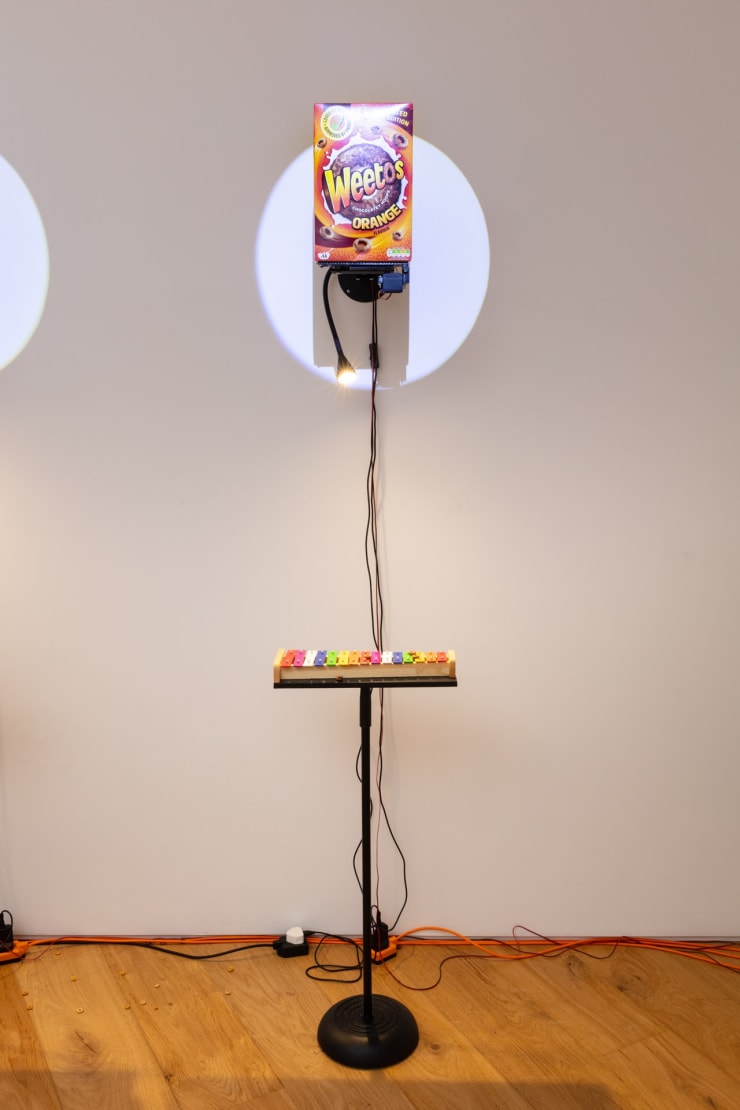 Clara Hastrup Do-Re-Mi-Fa-Ce-Re-Al (Weetos), 2023 Cereal, metal support structure, Arduinos, motors, 3D printed parts, xylophones, metal stand, spotlights