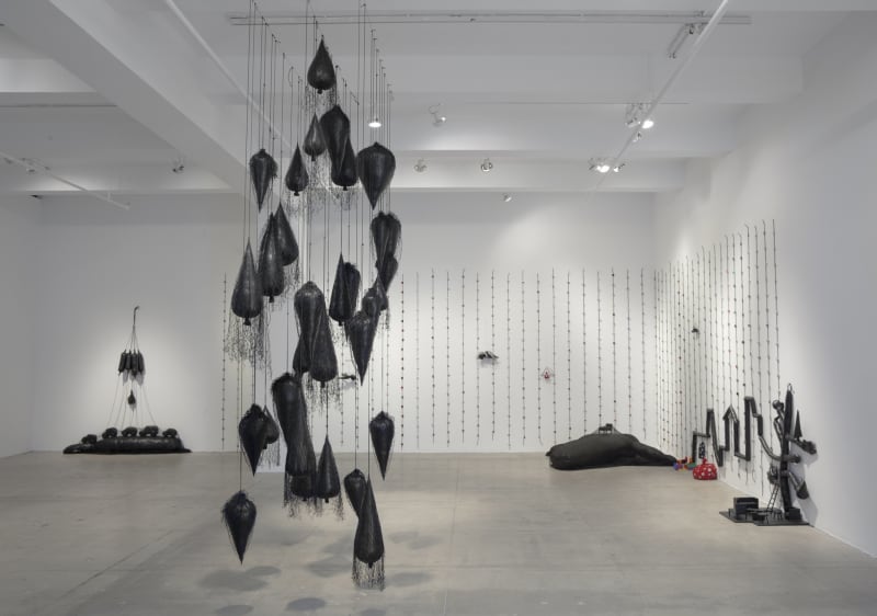 A room full of balloon-like sculptures of varying weight and structure, some nailed to the wall, some hanging from the ceiling.