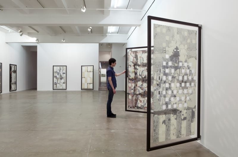 A man views the front and back of a large vertical painting installed on a hinge. 