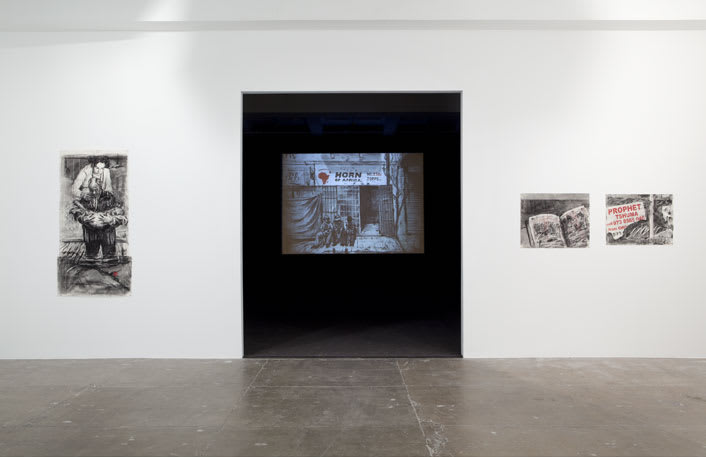 Gallery view of an entrance into a dark room with a large video installation, flanked by three charcoal drawings on paper.
