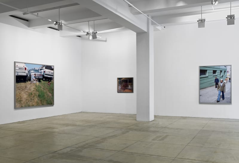 3 framed, color photographs of various sizes hang in the corner of a white room. There is a white column in the center.