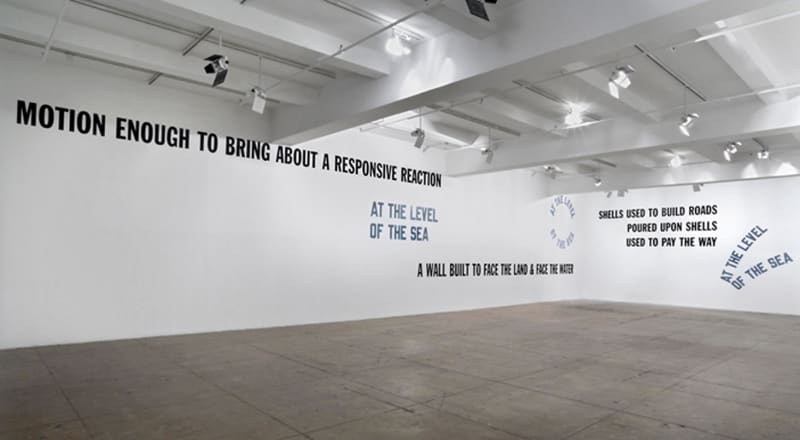 On the left wall starting at the top, black and blue text reads, motion enough to bring about a responsive reaction, at the level of the sea, a wall built to face the land & the water; on the right wall, black and blue texts reads, shells used to build ro