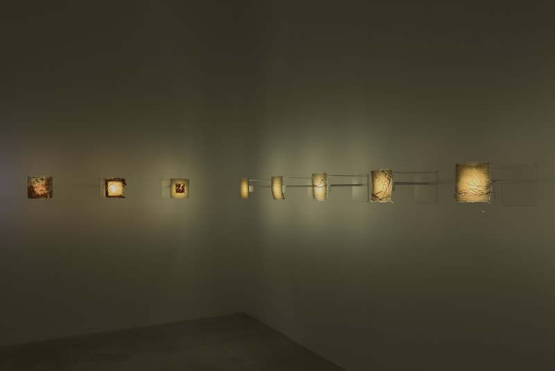 Eight small projectors behind various fabrics warmly illuminate a dimly lit room. 